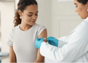 Healthcare worker administering vaccine to a smiling child in a medical setting